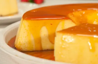 Pudim de leite cremoso com calda escorrendo em uma bandeja de para doces coberta com calda