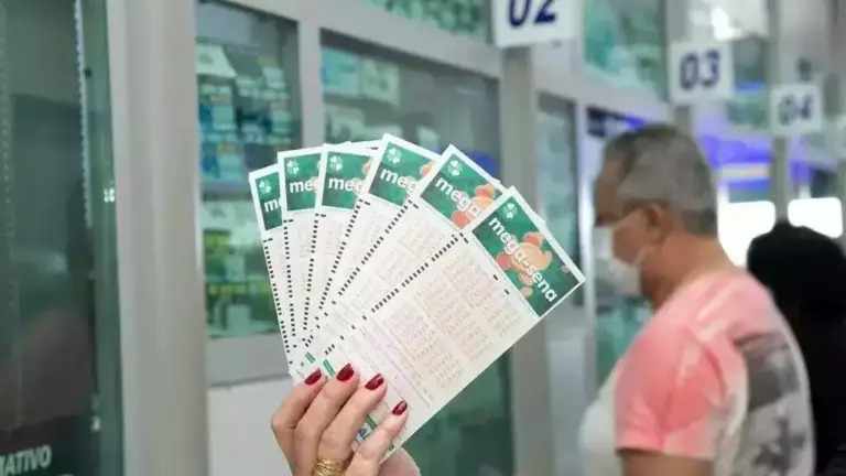 Uma pessoa segura vários bilhetes da Mega-Sena em frente a uma casa lotérica, enquanto um homem faz uma aposta no caixa.