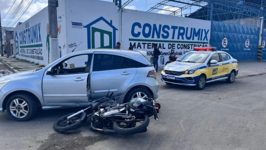 Motocicleta caída ao lado de carro prata após colisão em rua de Aracaju com viatura da SMTT presente no local em junho de 2026