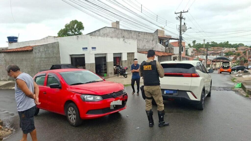 Agente da SMTT de Aracaju de costas entre carro vermelho e SUV branco após colisão em rua residencial durante atendimento de sinistro em junho de 2026