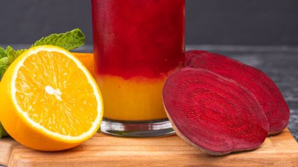 Suco de beterraba e laranja sendo misturado em copo de vidro
